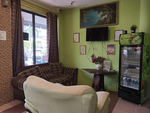 un soggiorno con divano, sedie e frigorifero di OYO 90860 Wawasan Inn a Sarikei