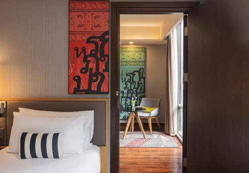 曼谷的住宿－Travelodge Sukhumvit 11，一间卧室配有一张床,另一间卧室配有椅子