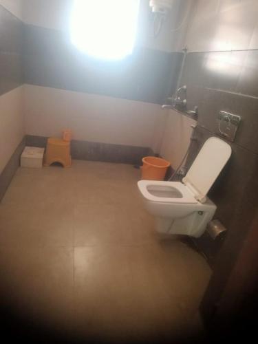 uma casa de banho com um WC branco e um banco amarelo em Lakshya Resort em Dīgod