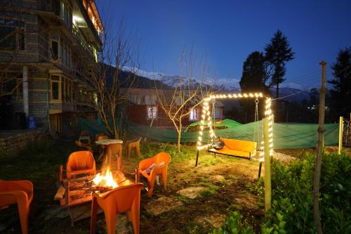 Shree Ram Cottage, Manali ! 1,2,3 Bedroom Luxury Cottages Available في مانالي: مجموعة من الكراسي والأضواء في الفناء في الليل