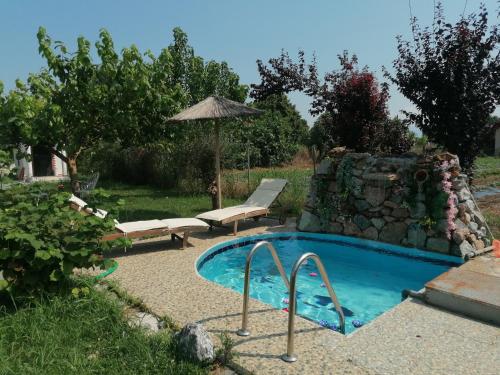 a swimming pool with two chairs and an umbrella at H BIΛΑ ΤΩΝ ΟΝΕΙΡΩΝ ΣΟΥ-999 THE VILLA OF YOURS Dreams 999 in Drama