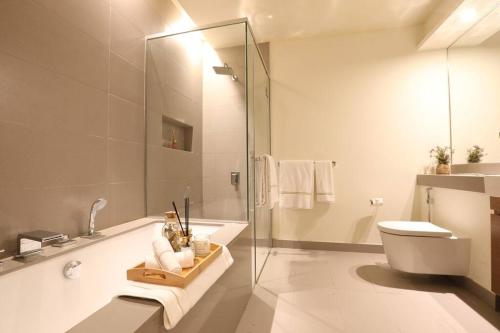 a bathroom with a glass shower and a toilet at Manzil - Sleek 2BR nr Downtown & Dubai Mall in Dubai