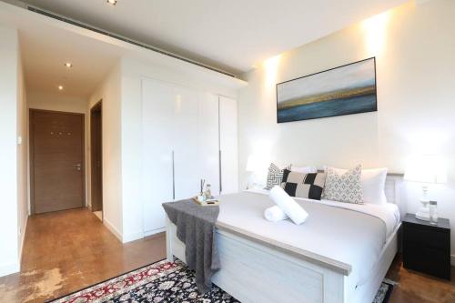 Un dormitorio con una cama blanca y una pintura en la pared en Manzil - Sleek 2BR nr Downtown & Dubai Mall en Dubái