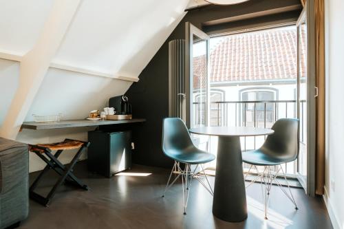 Habitación con mesa, sillas y ventana en Texels Goud Deluxe Suites en Den Burg