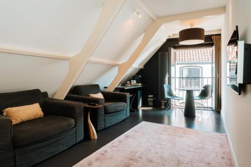 a living room with two couches and a table at 't Hoekie Suites in Den Burg