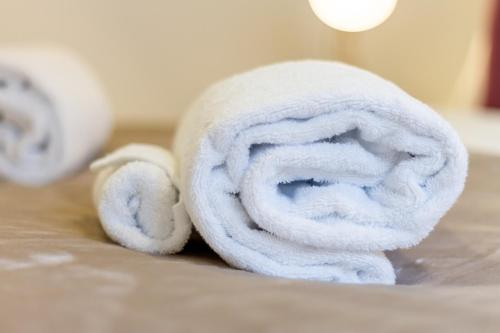 a roll of white towels sitting on a bed at An Easy Walk to the CBD - 2 Bed, 2 Bathroom in Christchurch