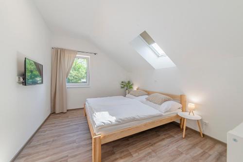 ein weißes Schlafzimmer mit einem Bett und einem Fenster in der Unterkunft Náš Sklep in Brod nad Dyjí