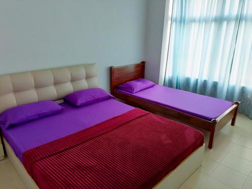 2 letti in una camera con lenzuola viola e finestra di SugarStay Homestay Teluk Kemang a Port Dickson