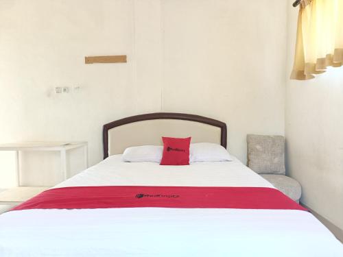 Una cama con una almohada roja encima. en RedDoorz Syariah near Rumah Sakit Umum Wisata UIT, en Balangberu