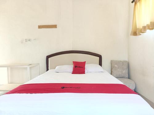 ein Bett mit einem roten Kissen darüber in der Unterkunft RedDoorz Syariah near Rumah Sakit Umum Wisata UIT in Balangberu
