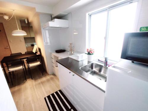 una cucina con lavandino e TV su frigorifero di 浦和STAY a Yono