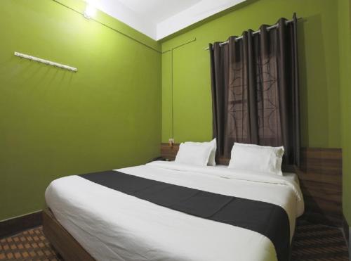 a bedroom with a large bed with green walls at B&B HOMES Guwahati in Guwahati