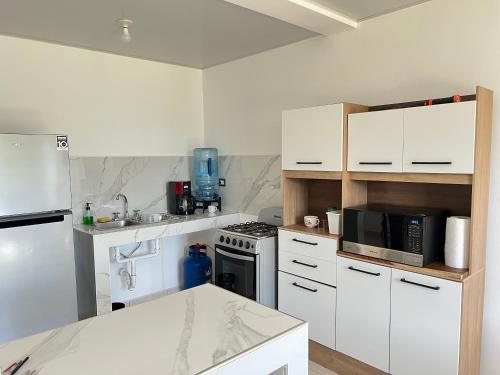 a kitchen with white cabinets and a stove top oven at Comfortable and roomy, in Sonsonate in Sonsonate