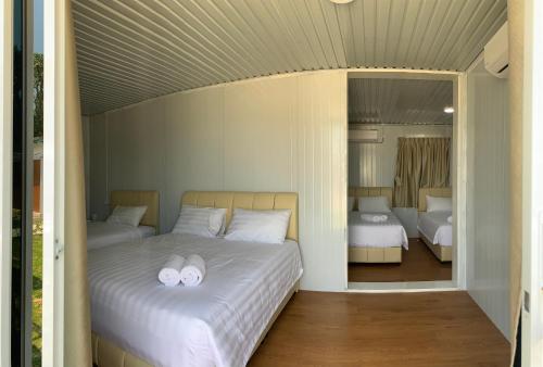 1 Schlafzimmer mit 2 Betten und weißen Kissen in der Unterkunft Meraga Cinta Kijal in Kijal