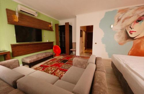 Inn OZZ Astana في أستانا: غرفة معيشة بها أريكة و لوحة لسيدة