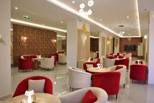 فندق الزوين - Alzuwain Hotel في عرعر: مطعم به كراسي وطاولات حمراء وبيضاء