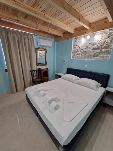 sypialnia z dużym białym łóżkiem i drewnianym sufitem w obiekcie Christos Katerina House w mieście Pitagorio
