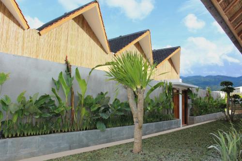 a house with a palm tree in front of it at Astakaia Cottage in Ciwidey
