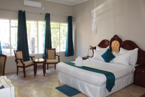 a bedroom with a large bed and chairs and windows at Fatmols Hotels in Lusaka