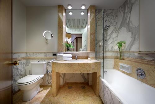 a bathroom with a tub, toilet, sink and mirror at Exe Majestic in Naples