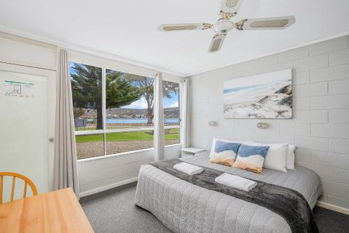 um quarto com uma cama e uma grande janela em Fishpen Holiday Apartments em Merimbula