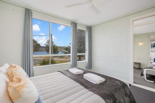 a bedroom with a bed and a large window at Fishpen Holiday Apartments in Merimbula