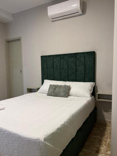 a bedroom with a large bed with a green headboard at HOTEl LA CANDELARIA ROOM HOUSE in Mangue