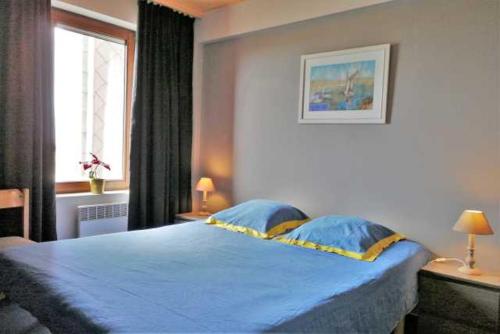 een slaapkamer met een blauw bed en een raam bij De Strandwandeling 0203 Appartement met frontaal zeezicht in Oostende