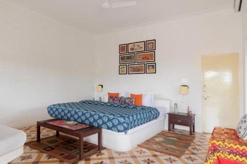 1 dormitorio con 1 cama con edredón azul en StayVista's Gaudhuli Farmstay - Outdoor Pool & Terrace with View, 