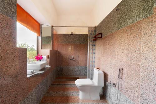 y baño con aseo y lavamanos. en StayVista's Gaudhuli Farmstay - Outdoor Pool & Terrace with View, 