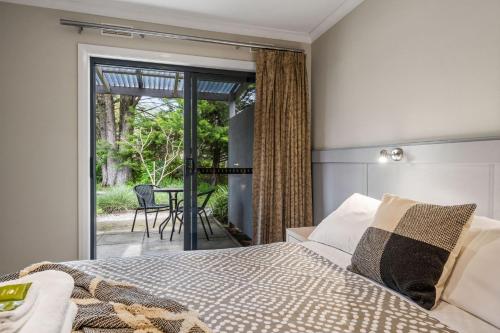 een slaapkamer met een bed en een patio met een tafel bij Grevillea Gardens Unit 4 in Bright