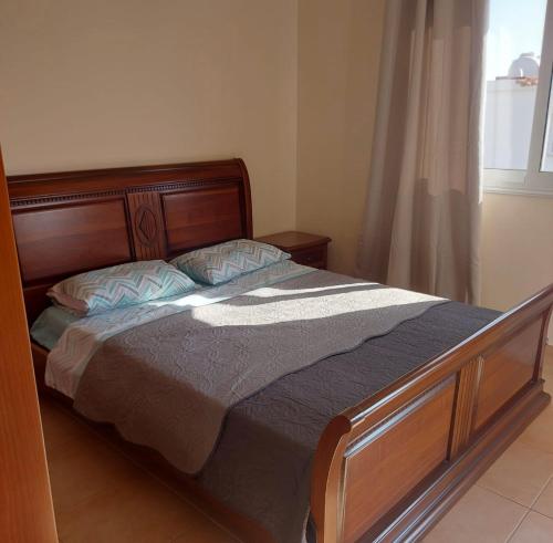 1 dormitorio con cama con marco de madera y ventana en The T Villa, en Protaras