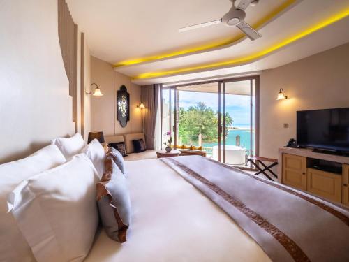 a living room with a couch and a tv at Devasom Khao Lak Beach Resort & Villas in Khao Lak