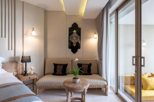 a bedroom with a bed and a chair and a table at Devasom Khao Lak Beach Resort & Villas in Khao Lak