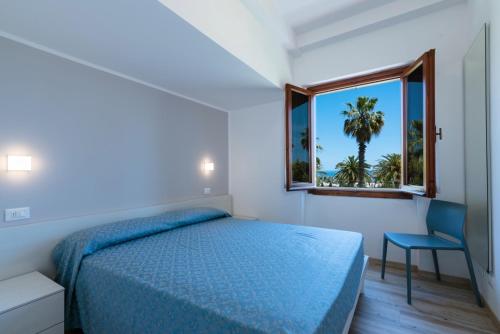 a bedroom with a bed and a window with a palm tree at Residence Elle in San Benedetto del Tronto
