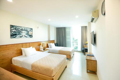 a hotel room with two beds and a television at Mia Hotel in Ho Chi Minh City