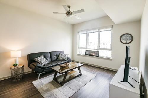 sala de estar con sofá negro y TV en Uptown Furnished Apartments near BOA Stadium apts, en Charlotte