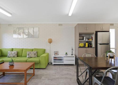 a living room with a green couch and a kitchen at Serene Nature Retreat in Rhyll