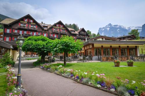 un gran edificio con flores delante en Romantik Hotel Schweizerhof, en Grindelwald