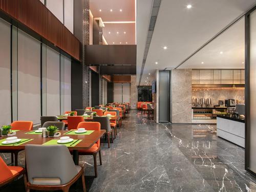 a restaurant with tables and chairs and a kitchen at Hampton by Hilton Foshan Dali in Foshan