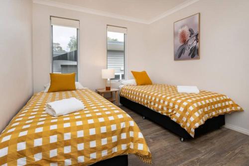 two beds in a room with yellow and white sheets at Viente @ Cape Villas Dunsborough in Dunsborough