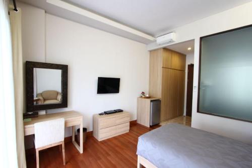 Habitación con cama, escritorio y TV. en Via Renata Panglima Polim en Yakarta