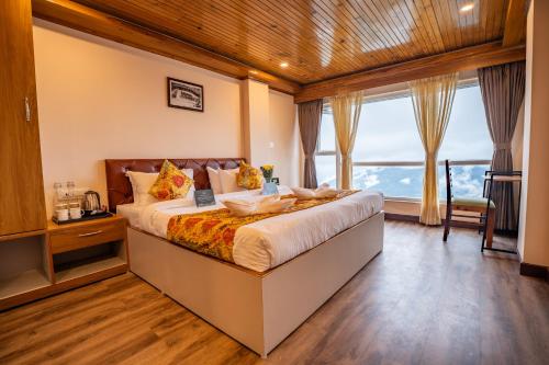 sypialnia z dużym łóżkiem i dużym oknem w obiekcie Muscatel Stardust - Chowrasta Mall Road w mieście Dardżyling