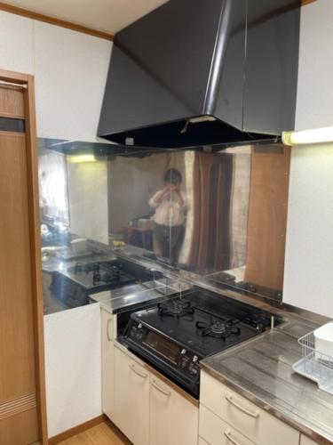 a kitchen with a stove and a person in the background at Family Resort Apartment in Funabashi