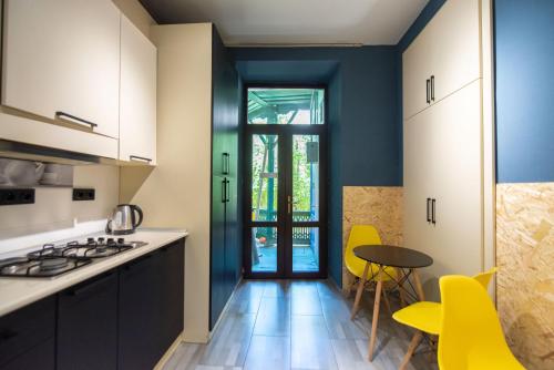 een keuken met blauwe muren en een tafel en gele stoelen bij Gallery Hostel Tbilisi in Tbilisi City