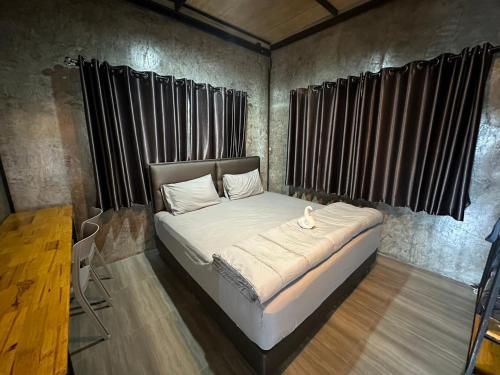 Cama en habitación con cortinas negras en The Nack Resort & Pool Villa บางบัวทอง, en Nonthaburi