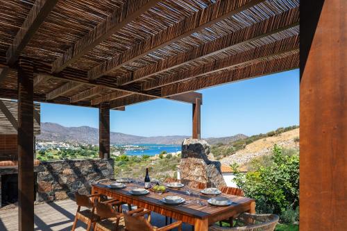 a wooden table on a patio with a view of the ocean at Villa Katy in Agios Nikolaos