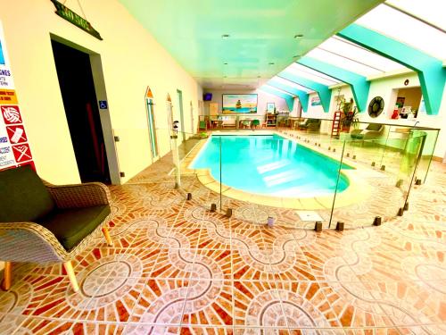 una piscina en una habitación con sofá y silla en Hotel Aux Rochers de l'Ocean, en Givrand