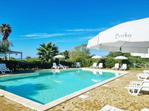 a swimming pool with chairs and an umbrella at Barko Apartments & Suites in Steccato