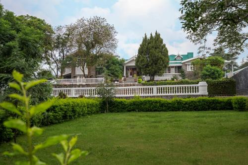 a white fence in front of a house with a yard at Brij Anayra Dharamshala - A Himalayan Luxury Retreat in Dharamshala